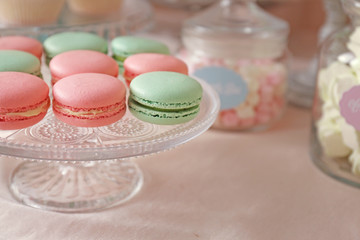 Glass stand with macarons on table with different sweets