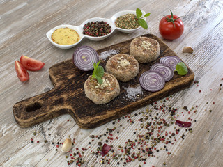 Minced meat medallions on a wooden table. 