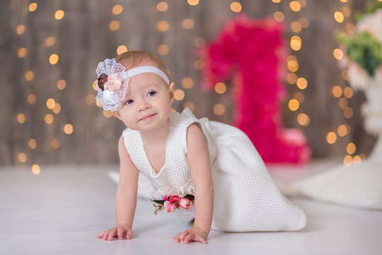 Cute baby girl 1-2 year old sitting on floor with pink balloons in room over white. Isolated. Birthday party. Celebration. Happy birthday baby, Little girl with group ball. Play room.
