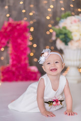 Cute baby girl 1-2 year old sitting on floor with pink balloons in room over white. Isolated. Birthday party. Celebration. Happy birthday baby, Little girl with group ball. Play room.