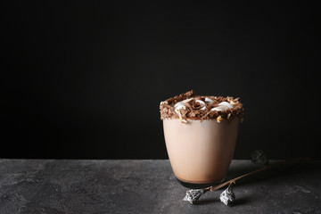 Cup of tasty cocoa drink and marshmallow on grey table against black background
