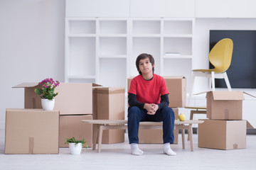 boy sitting on the table with cardboard boxes around him