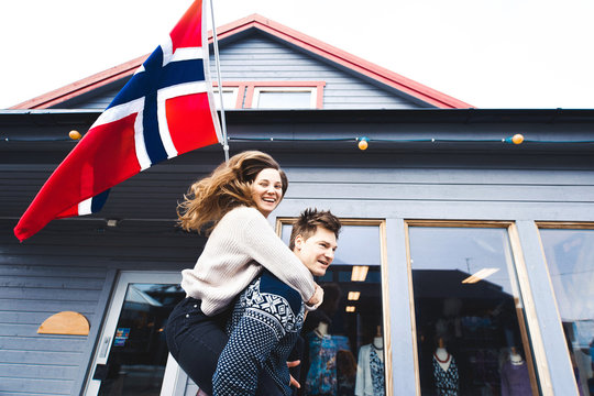 closeup couple girl and man in love Scandinavian style, sweater with deer, kissing and holding hands close a beautiful young blond hair Norwegian flag on a background of happiness