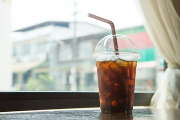 Delicious ice coffee americano on wood table place near window.