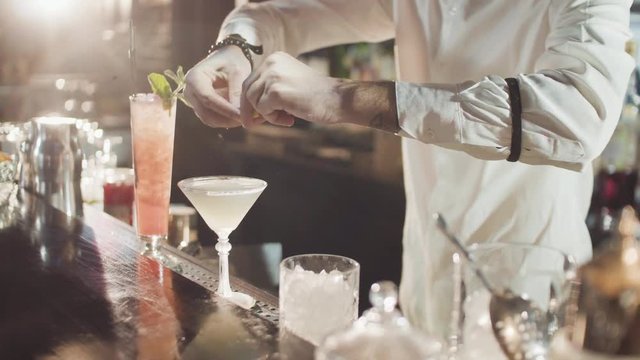 20s bartender is preparing cocktail in a night bar