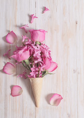 Flowers in a waffle cone on white wooden background