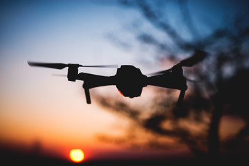 Drone flying into the sunset. Silhouette of drone against colorful sky.