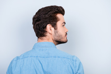 Back view of stylish young brunet man with modern hairstyle on light blue background
