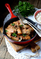 Fried pork belly in a cast-iron frying pan with onion, garlic and soy sauce.