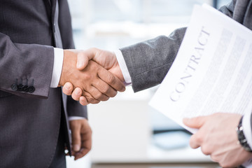 cropped view of businessmen shaking hands in office, business meeting concept
