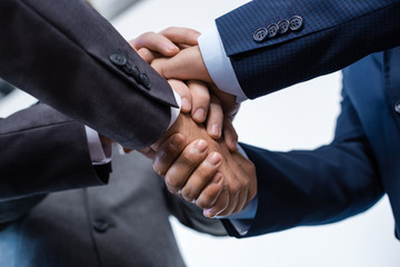 Close-up partial view of businesspeople in formal wear stacking hands together, business concept