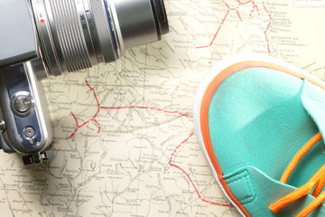 Green color sport shoe with orange color shoe cable and camera put on old and vintage paper map.