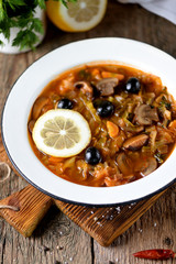 Traditional Russian soup solyanka made from cabbage, fresh and dried mushrooms with olives, lemon and capers.
