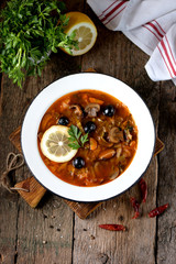 Traditional Russian soup solyanka made from cabbage, fresh and dried mushrooms with olives, lemon and capers.