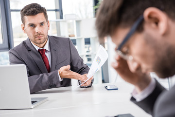 unsatisfied boss looking at upset colleague at business meeting