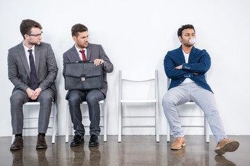 young businessmen sitting on chairs in waiting room, business concept