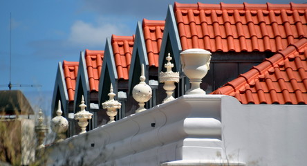 Reihe von Dächern mit roten Schindeln hinter einer weißen Mauer 