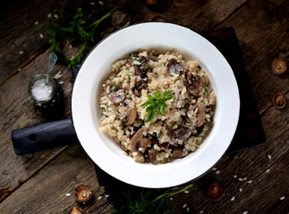 Risotto with mushrooms on an old wooden background. Rustic style.