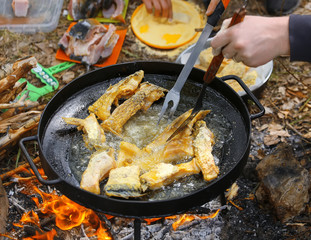 Boiling in oil on opened fire, frying fish fillet.