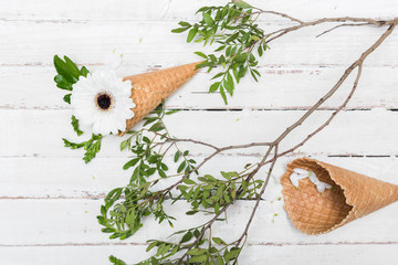 Top view of beautiful chrysanthemum flower with green leaves and wafer cones on wooden background