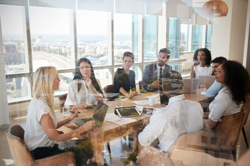 Businesswoman Leads Meeting Around Table Shot Through Door