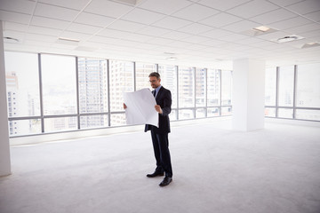Fototapeta na wymiar Male Architect In Modern Empty Office Looking At Plans