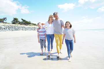 Happy family of four walking on sandy beach