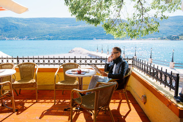 Young man using his smartphone while sitting in a  coast cafe 