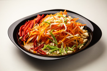 Fresh vegetable salad with peppers, carrots, sprouts, nuts, herbs and seeds. Healthy vegetarian food on light background. Theme of raw food, live and healthy eating