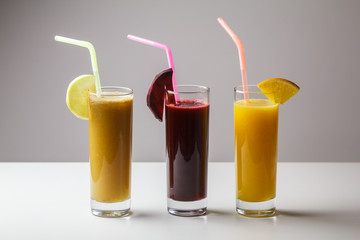 Healthy eating juicing cleanse diet trend concept - fruit and vegetable juice glasses with straw. Theme of raw food, live food background