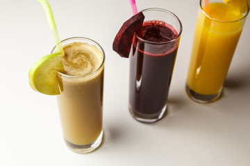 Healthy eating juicing cleanse diet trend concept - fruit and vegetable juice glasses with straw. Theme of raw food, live food background