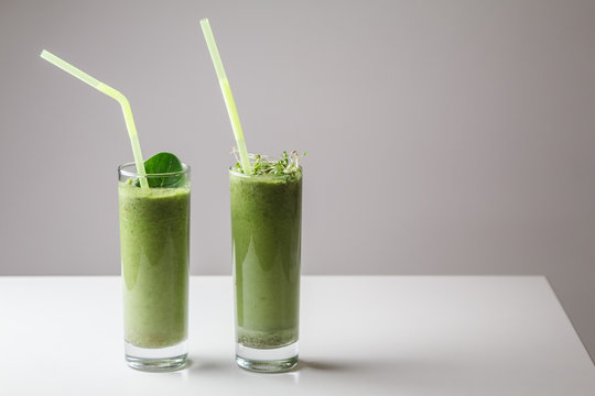 Freshly blended green fruit smoothie in glass with straw. Theme of raw food, live food, healthy eating background