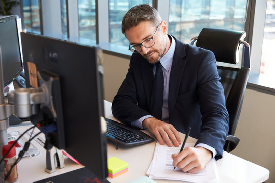 Businessman Sitting At Desk In Office Using Computer