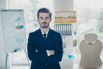 Naklejka na ściany i meble Concept of successful young confident businessman. Concentrated man with crossed arms standing in front of shelves full of folders and board with graphs