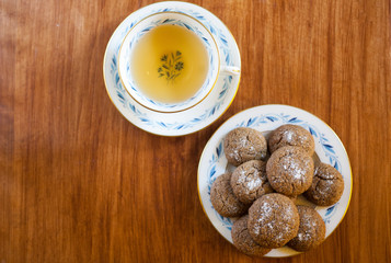 a plate of Molasses cookies with green tea in a vintage porcelain teacup on wooden table