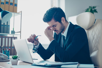 Portrait of young minded overworked student  holding his glasses and touching nose-bridge while...