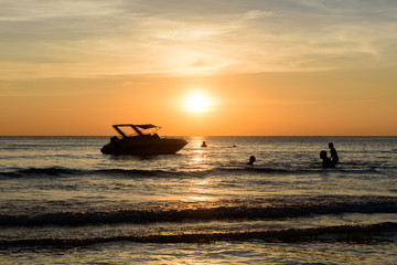 Chao Lao Beach at Chanthaburi  Dec 18,2016 : People swim near shadow boat and light sunset on the beach,THAILAND
