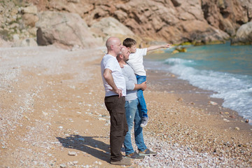 Family of grandfather father and son on a rocky beach on vacation enjoying time together