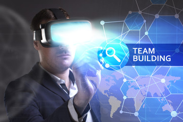 Business, Technology, Internet and network concept. Young businessman working in virtual reality glasses sees the inscription: Team building
