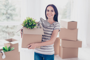 Cheerful young pretty brunette is packing her stuff at the box to move to new place. She is happy and can`t wait
