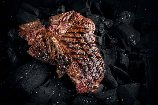 Grilling A Tasty Tender Marinated T-bone Steak On A Coals. Close Up View