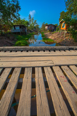 A wooden bridge across a canal in a farmer's village.