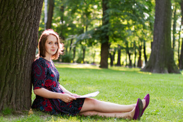 young woman sitting under a tree