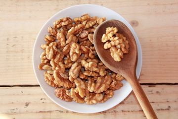 Walnuts on a White plate with a wooden spoon