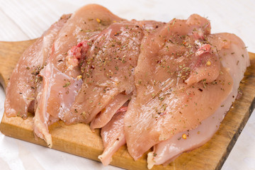 Raw chicken breasts on the wooden board spiced for barbecue