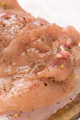 Raw chicken breasts on the wooden board spiced for barbecue