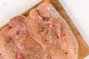 Raw chicken breasts on the wooden board spiced for barbecue