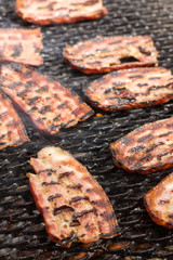 Selective focus on the bacon on the hot grill with shallow depth of view
