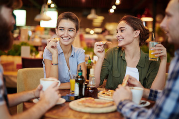 Long-awaited get-together of friends: they sitting at pizza restaurant table and having small talk, waist-up portrait