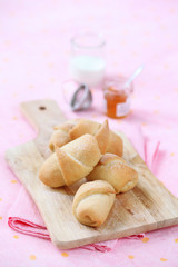 Hazelnut Roll Buns on wooden board, on light pink background.